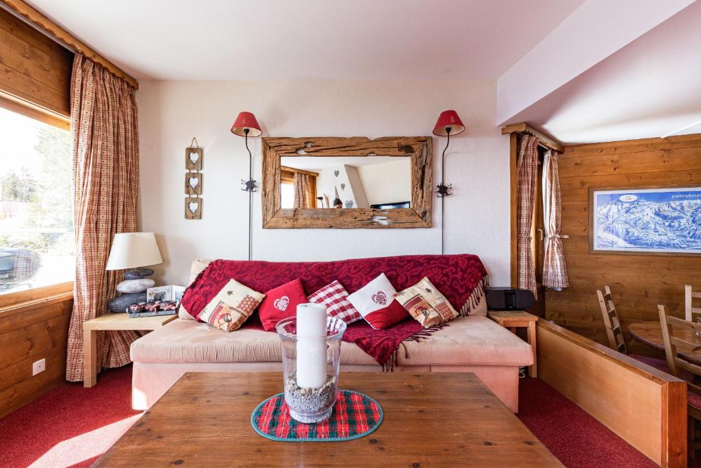 Spacious Stylish apartment for 8 by Avoriaz Chalets في أفورياز: غرفة معيشة مع أريكة حمراء وطاولة