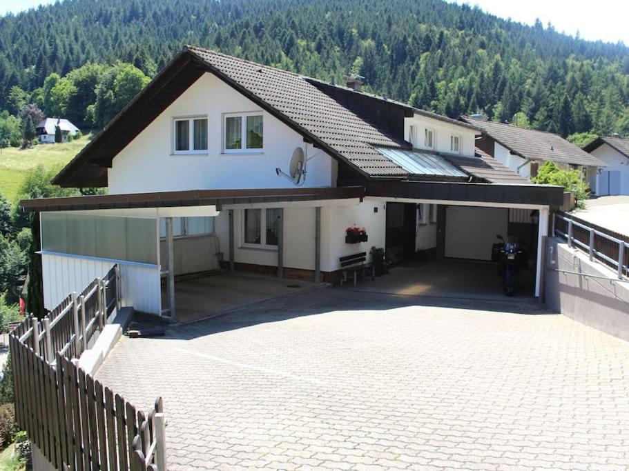 een wit huis met een oprit en een hek bij Ferienwohnung Schwarzwaldblick in Bad Rippoldsau-Schapbach