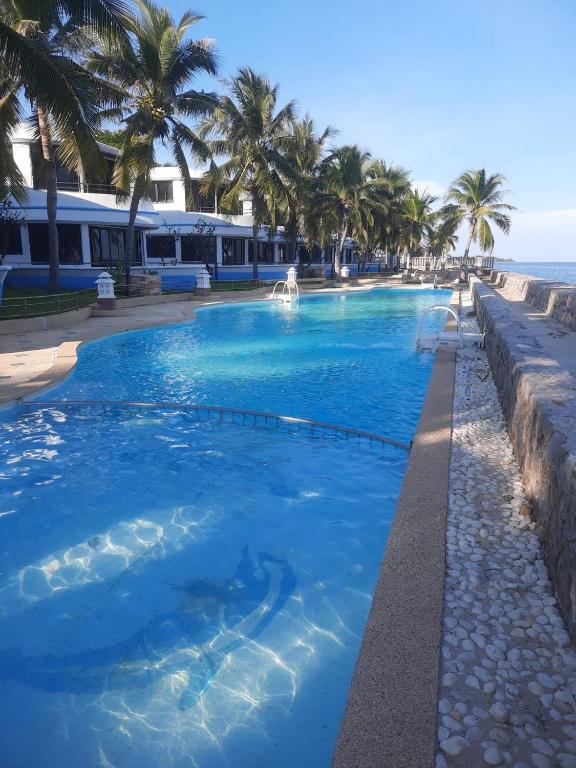a swimming pool with palm trees and the ocean at บ้านนาวาภิรมย์ ชะอํา in Ban Khlong Khot
