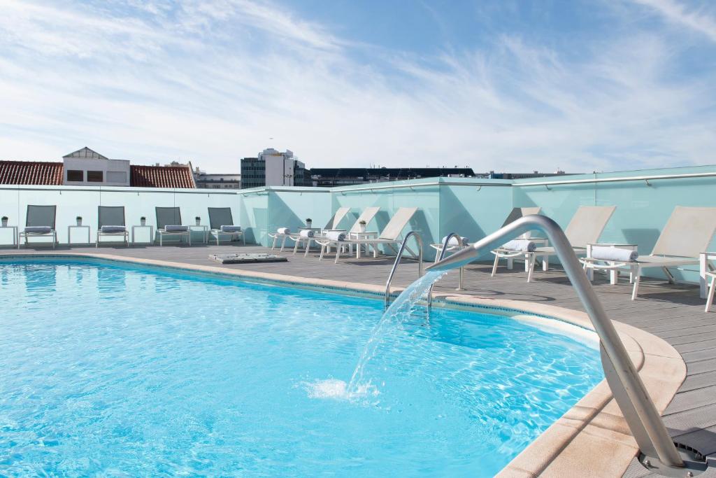 a pool with a water fountain on top of a building at SANA Reno Hotel in Lisbon