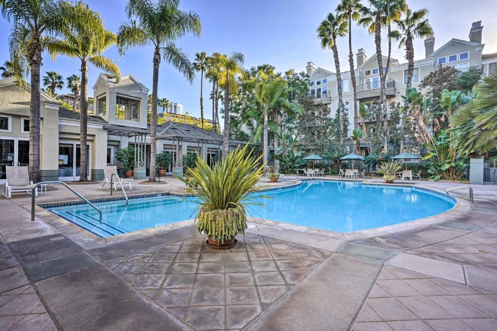 a swimming pool with palm trees in front of a building at Serene Irvine Retreat with Heated Pool Access! in Irvine