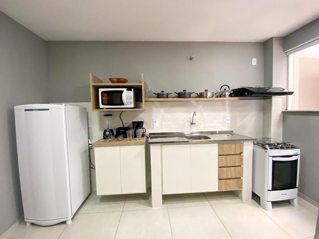 a kitchen with a white refrigerator and a microwave at Dois quartos com varanda - super espaçoso in Barra do Piraí