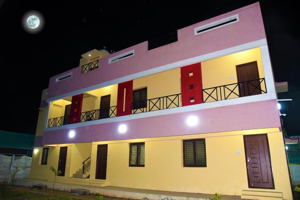 un gran edificio blanco con balcón por la noche en Kumbakonam Inn Hotels - Kumbakonam Inn Stay, en Kumbakonam