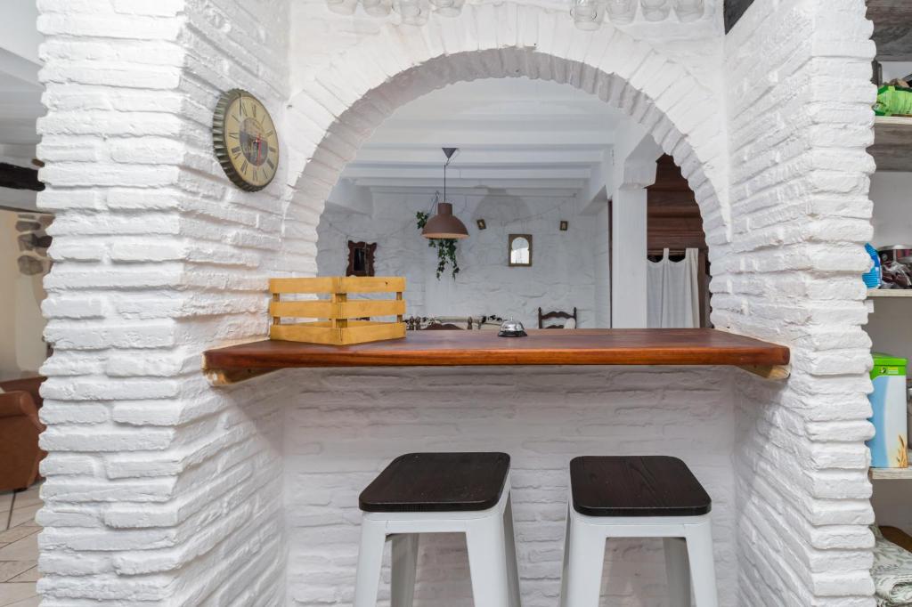 a bar in a white brick wall with two stools at Casa Camino del Dobra, Centro de Cantabria in Viérnoles