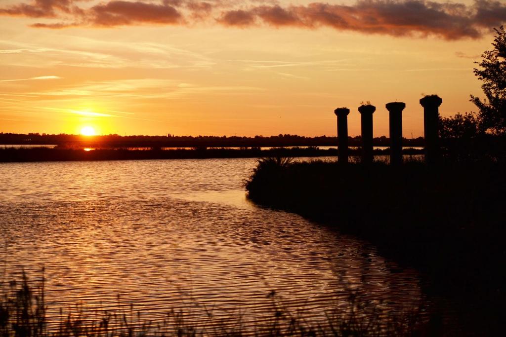 a sunset over a body of water with pillars at B&B Le Saline Bed & Breakfast in Cervia