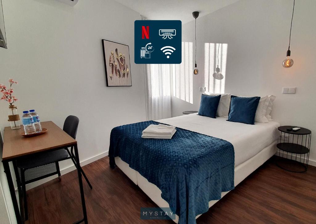 ein Schlafzimmer mit einem Bett und einem Tisch und einem Schild in der Unterkunft Seasons Porto-Gaia by MyStay in Vila Nova de Gaia