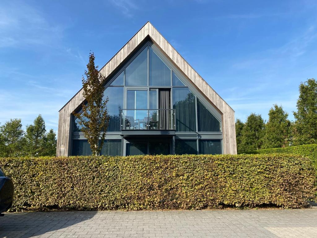 a glass house with a roof over a hedge at ParelDuyn in Oostkapelle