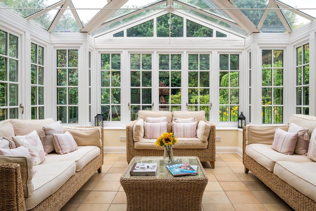 a conservatory with couches and tables and windows at Pentre Bach in Llansantffraid Glan Conwy