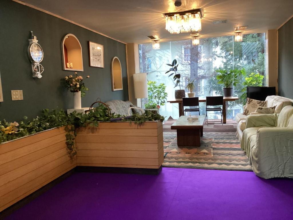 湯沢町にあるプチホテル雪ッ子荘の紫のカーペット敷きのリビングルーム(ソファ付)