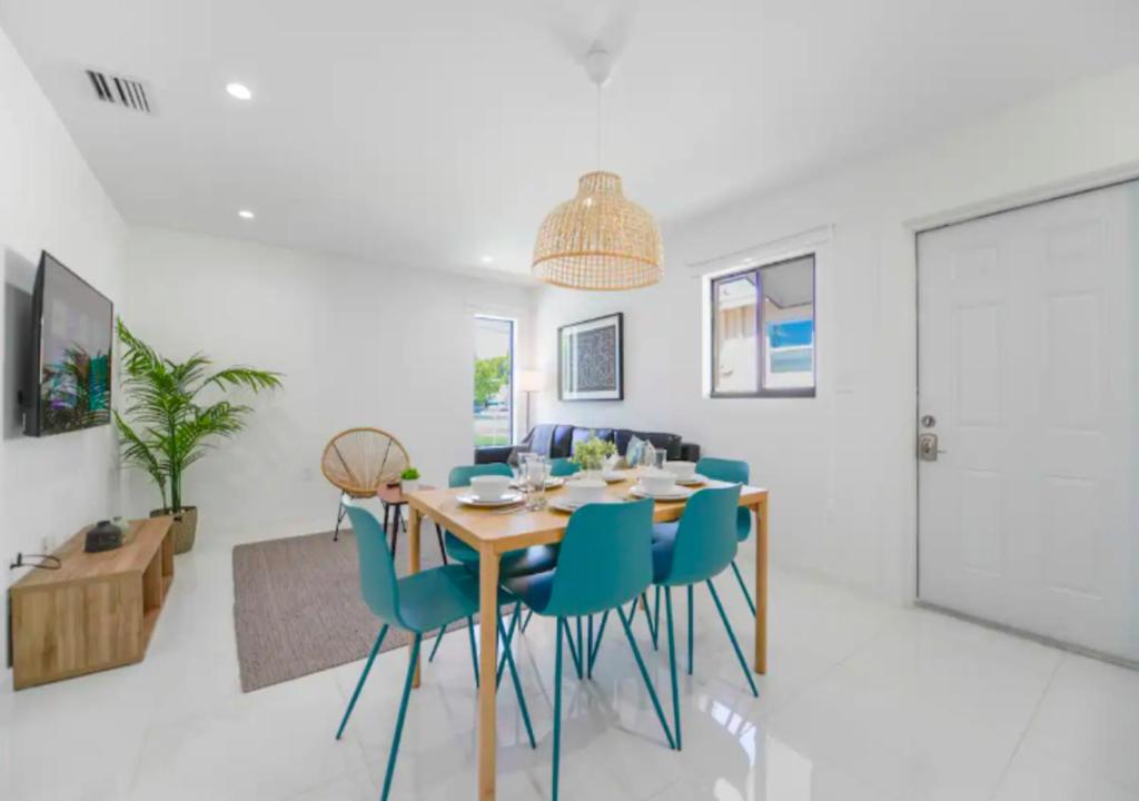 uma sala de jantar com uma mesa de madeira e cadeiras azuis em Fantastic Brand New 3BD Duplex In Miami em Miami