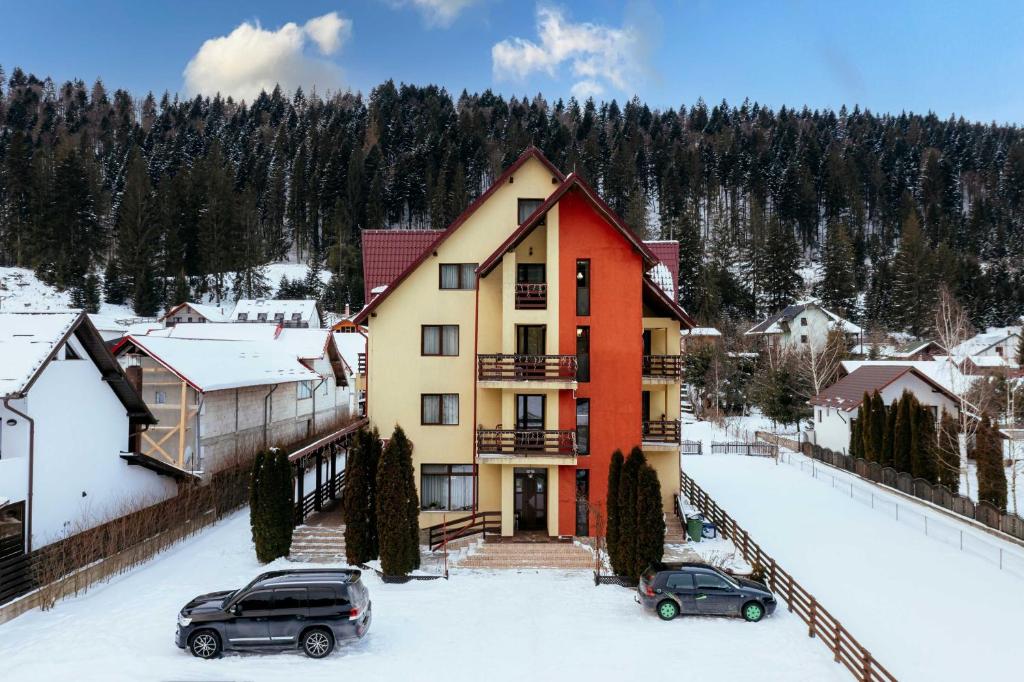 a house in the snow with two cars parked in front at Pension Valeria in Voronet