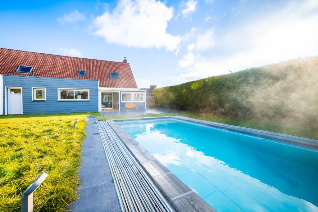 a swimming pool in front of a house at Grande maison avec piscine et jacuzzi à la campagne in Desvres