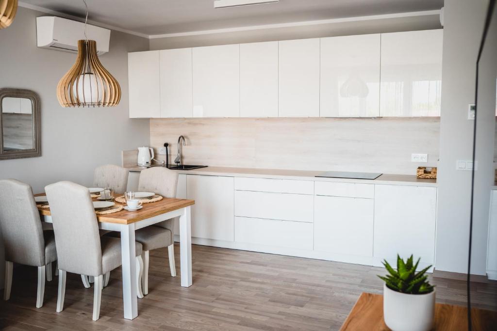 uma cozinha com armários brancos e uma mesa e cadeiras em Apartament Rezydencja Park 3 em Mielno