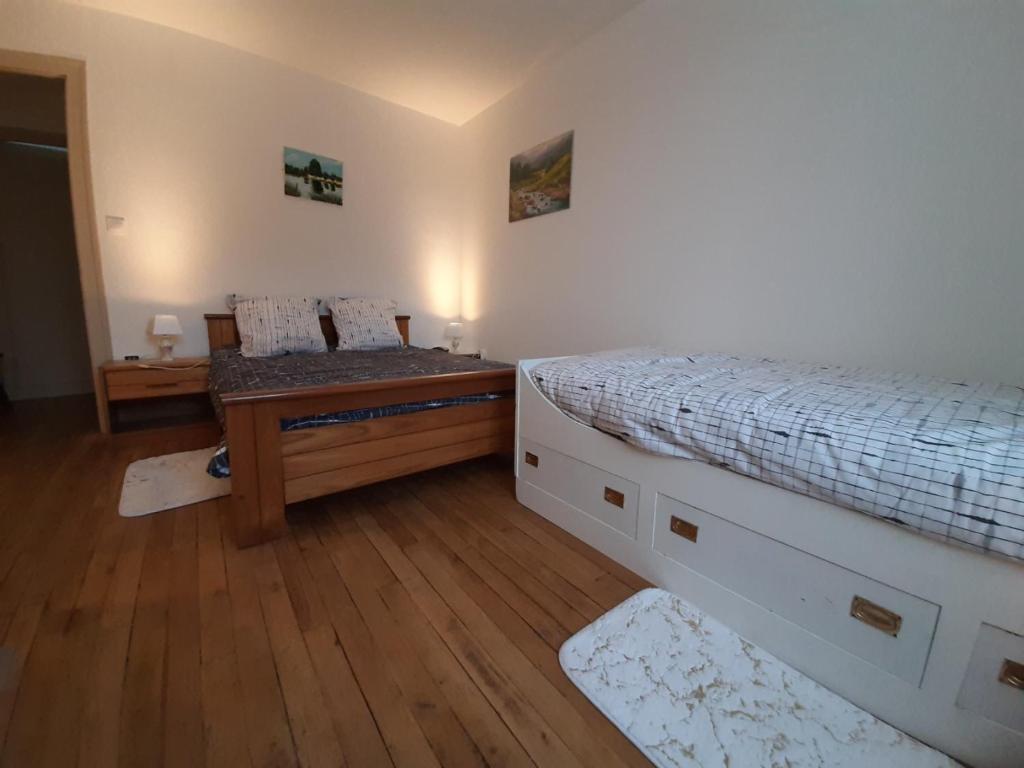 1 dormitorio con 2 camas y suelo de madera en CHARLES AU PREMIER, en Le Mêle-sur-Sarthe