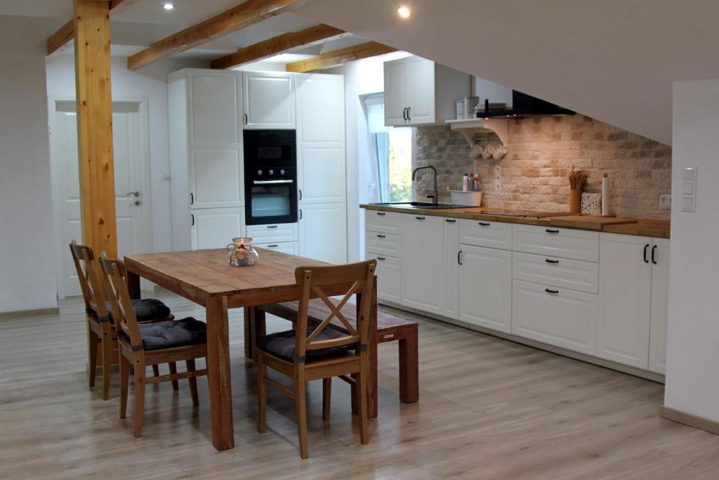 una cocina con armarios blancos y una mesa y sillas de madera. en Ferienwohnung Stefanko, en Bernau