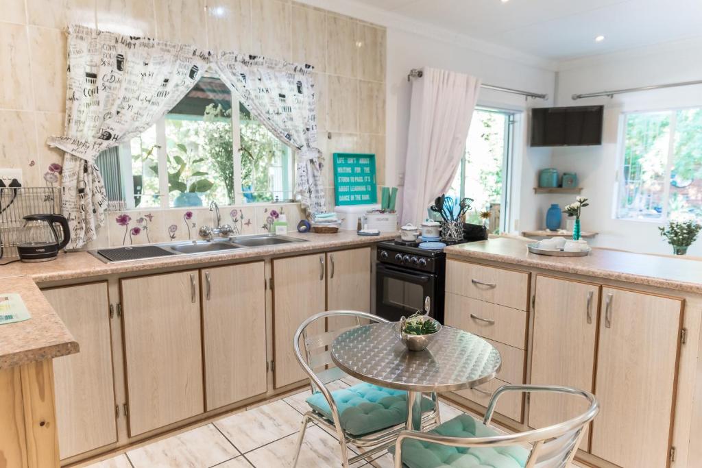 a kitchen with wooden cabinets and a table and chairs at Gabbys Cottage Guesthouse in Bloemfontein