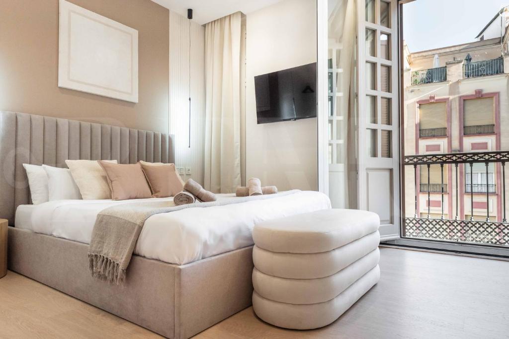 a bedroom with a bed with a stool and a tv at NEW Sophisticated apartment with balcony & city views by REMS in Málaga