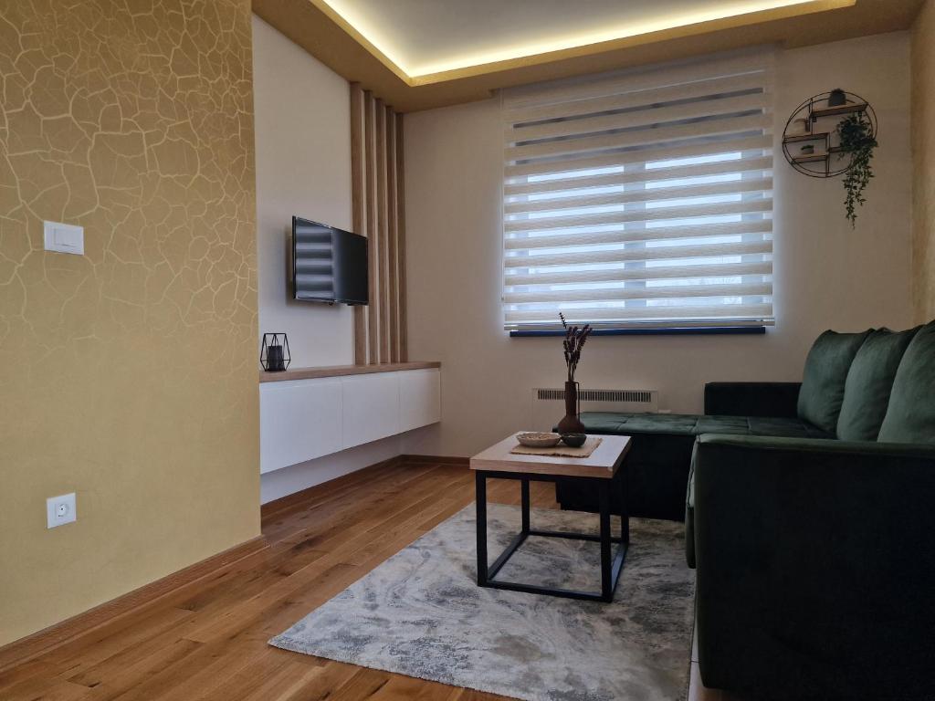 a living room with a green couch and a table at Hedonist Zlatibor Mountain Wellness & SPA in Zlatibor