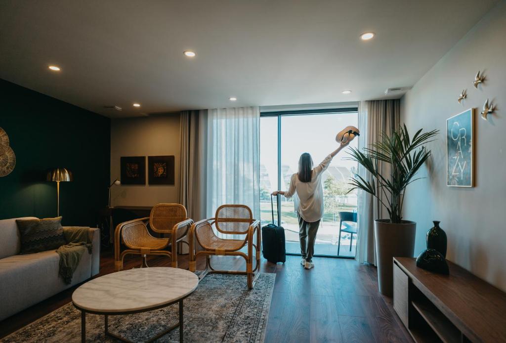 a woman standing in a living room looking out the window at XPT Águeda - Boutique Apartments in Águeda