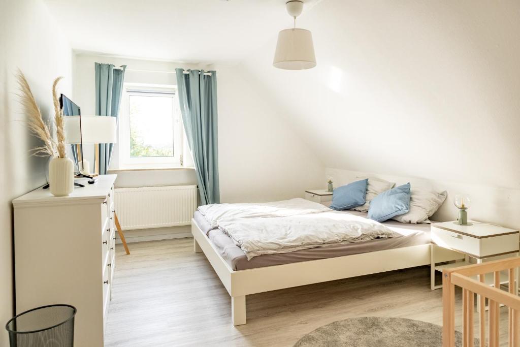 a white bedroom with a bed and a desk at Ferienhaus Tidenkieker in Nordstrand