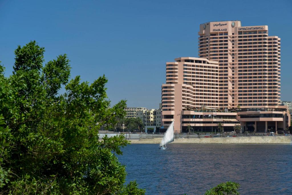 un pájaro blanco volando sobre un cuerpo de agua con edificios en InterContinental Cairo Semiramis, an IHG Hotel en El Cairo