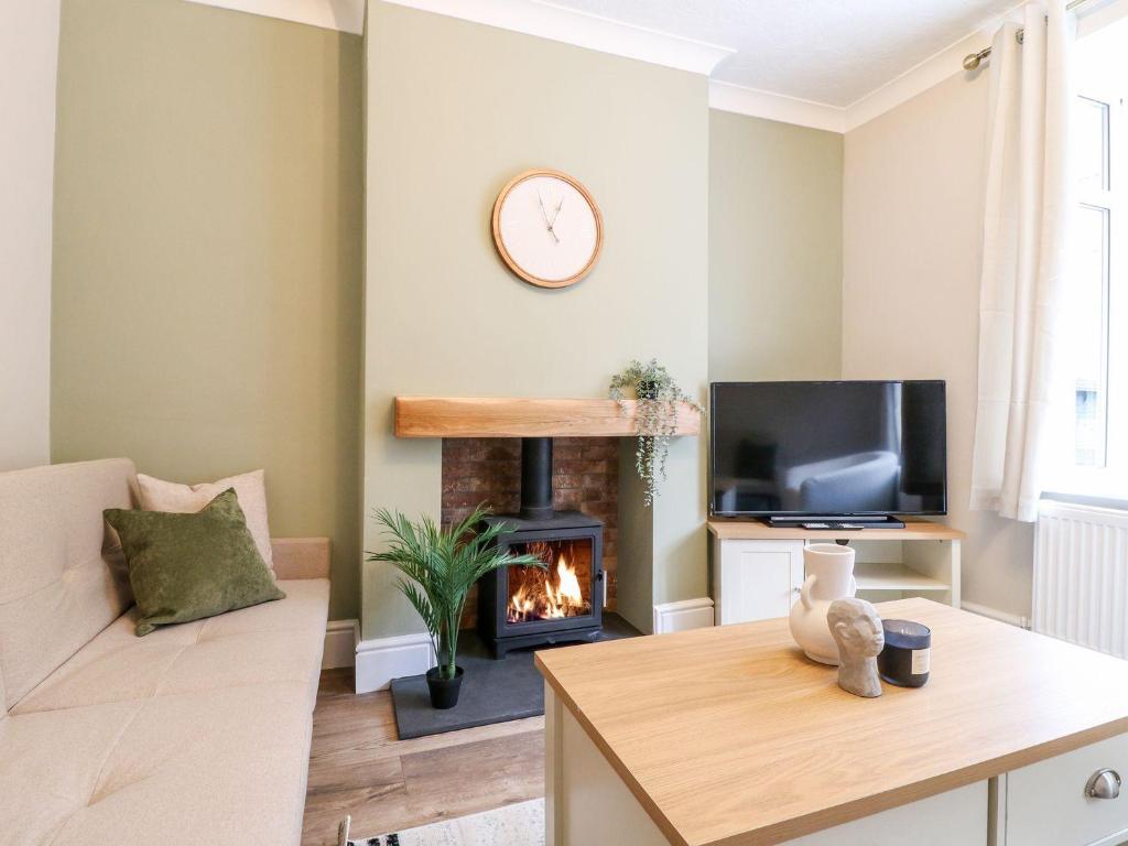 a living room with a fireplace and a tv at The Crooked Cottage in Ashbourne