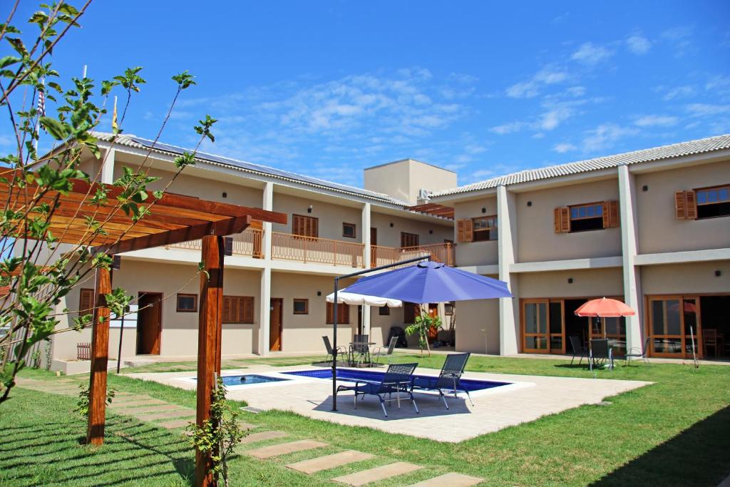 - une terrasse avec 2 chaises et un parasol en face d'un bâtiment dans l'établissement Pousada das Bandeiras, à Olímpia