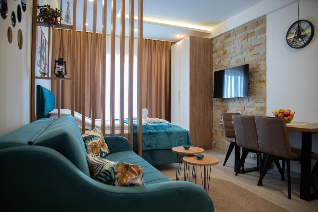 a living room with a blue couch and a bedroom at Apartman Larisa in Kopaonik