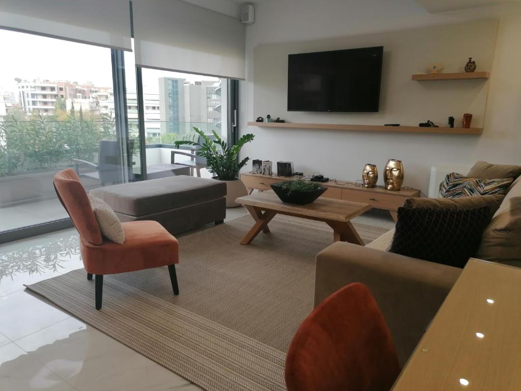 ein Wohnzimmer mit einem Sofa und einem TV in der Unterkunft The Lop Athens Holidays Luxury Suites in Athen