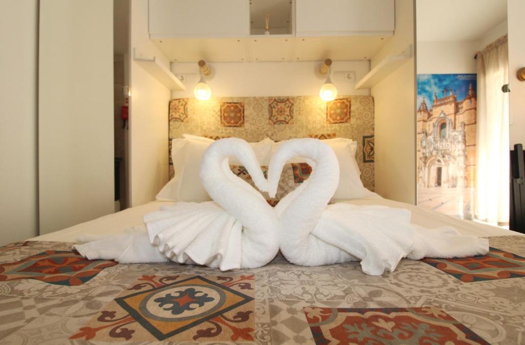 two white swans sitting on top of a bed at Casa Boytac by CosyCasa Praia Peniche in Peniche