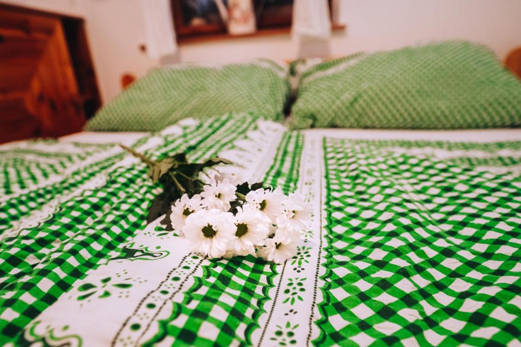 Una cama verde y blanca con flores blancas. en Apartmán u Rossniček Moravský kras, en Kulířov