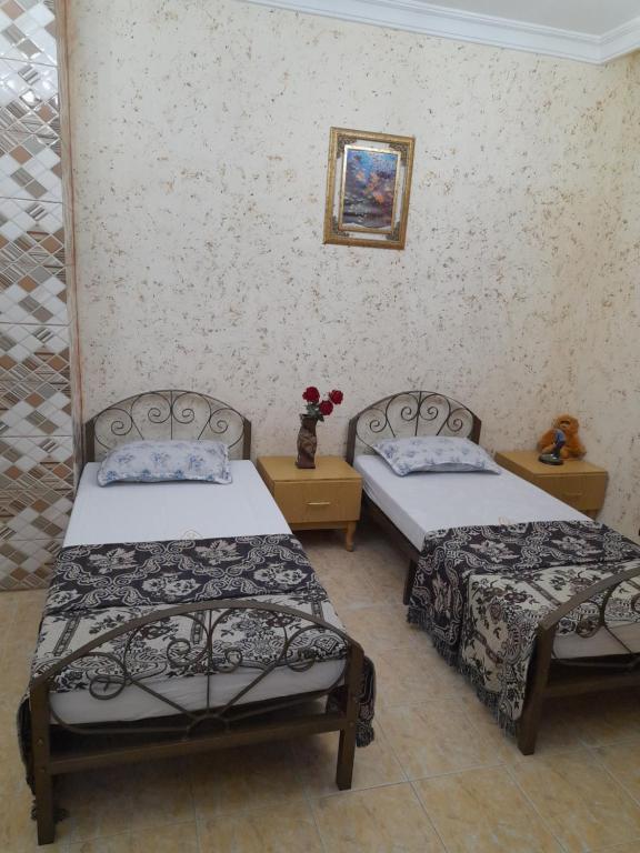two beds in a room with two tables at mini house in Aqaba