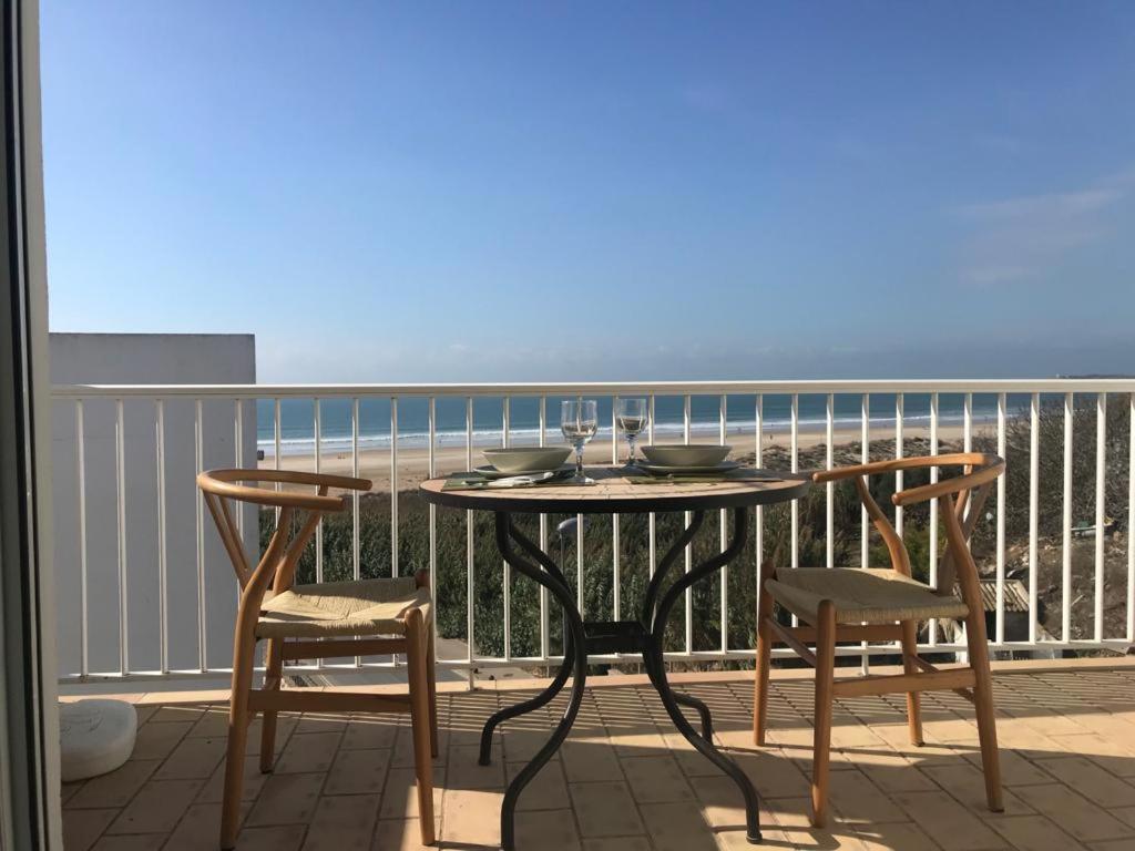 una mesa y sillas en un balcón con vistas al océano en Chorrillo III, en Conil de la Frontera