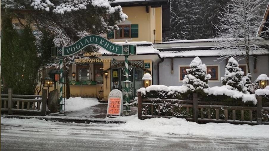 un cartello nella neve davanti a un edificio di Hotel Voglauerhof ad Abtenau