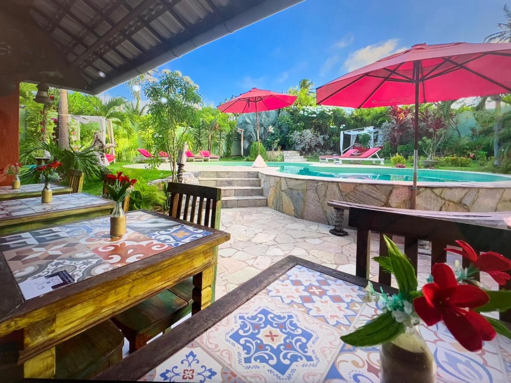 un patio con mesas, sombrillas y una piscina en Xainã Pousada de Charme en Cumbuco