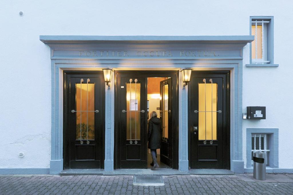 Una donna in piedi sulla porta di un palazzo di Fair Hotel Villa Diana a Francoforte sul Meno
