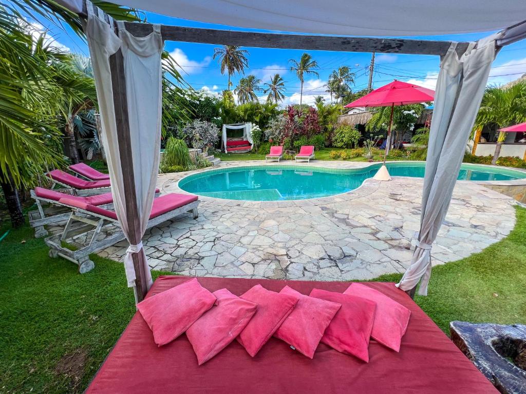 uma piscina com um monte de almofadas num cobertor vermelho em Xainã Pousada de Charme em Cumbuco