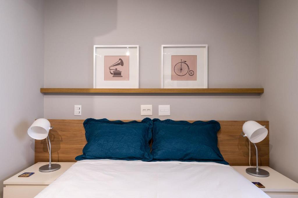 um quarto com 2 candeeiros e uma cama com almofadas azuis em VO13 - Apto Luxuoso e Aconchegante no Bom Retiro: Conforto em São Paulo