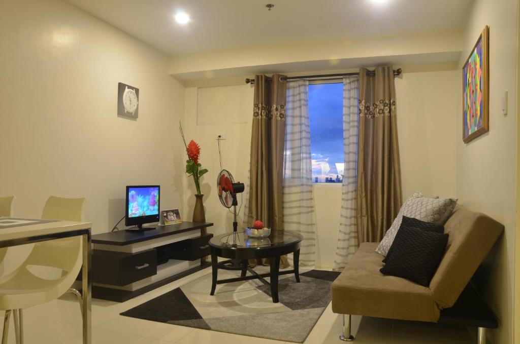 a living room with a couch and a table and a television at Gilmore Apartment at Princeton Residences Condominium in Manila