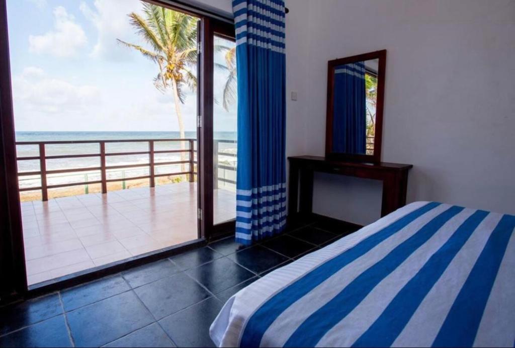 a bedroom with a bed and a view of the ocean at Reef Bungalow Hotel in Pamunugama