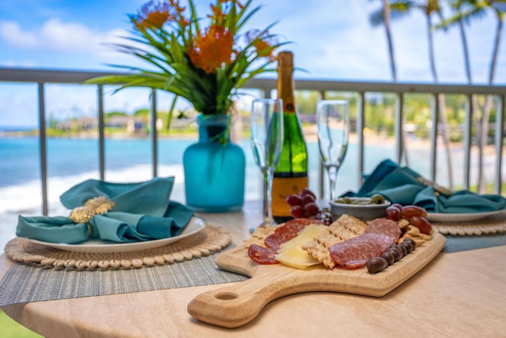 a table with plates of food and a bottle of wine at Napili Shores A202 OF Studio condo in Kahana