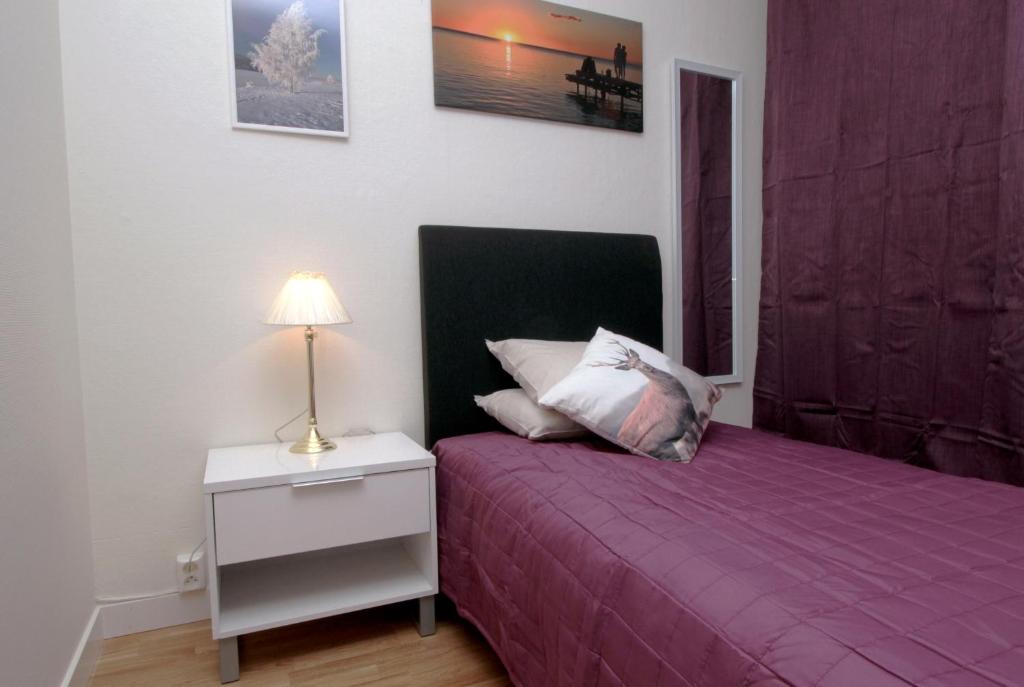 a bedroom with a purple bed and a nightstand with a lamp at Hotell Linden in Östersund
