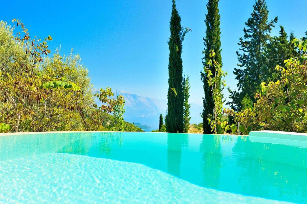 a swimming pool with trees and a mountain in the background at Mounty Island Villas in Lazaráta