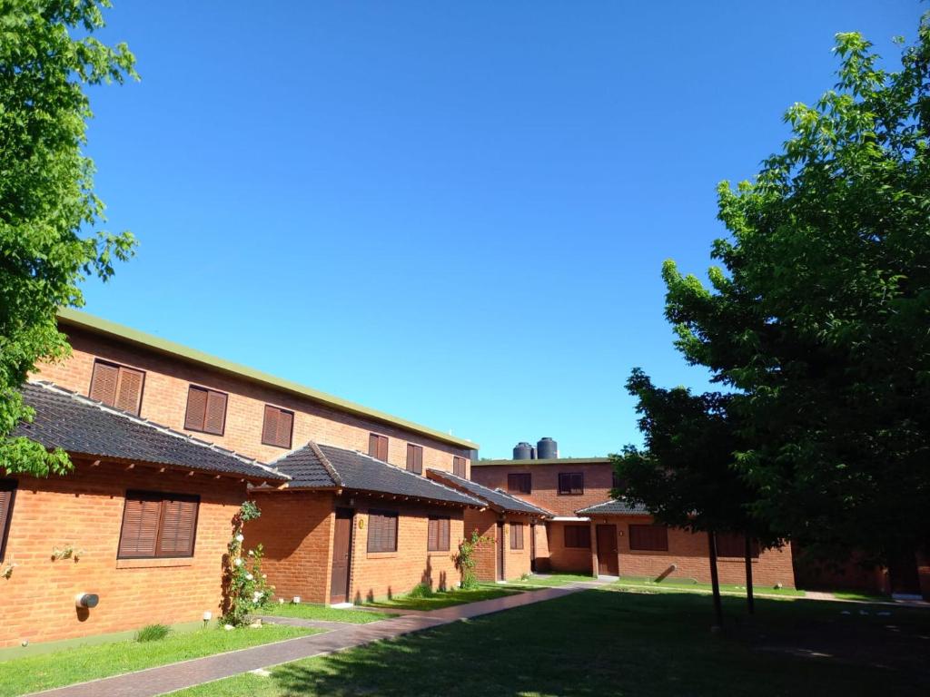 a group of buildings with trees in the foreground at Cabañas Brochero del Valle in Villa Cura Brochero