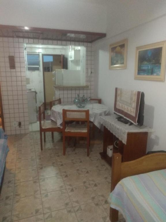 a living room with a table and chairs and a television at Kitinete em Itanhaem in Itanhaém