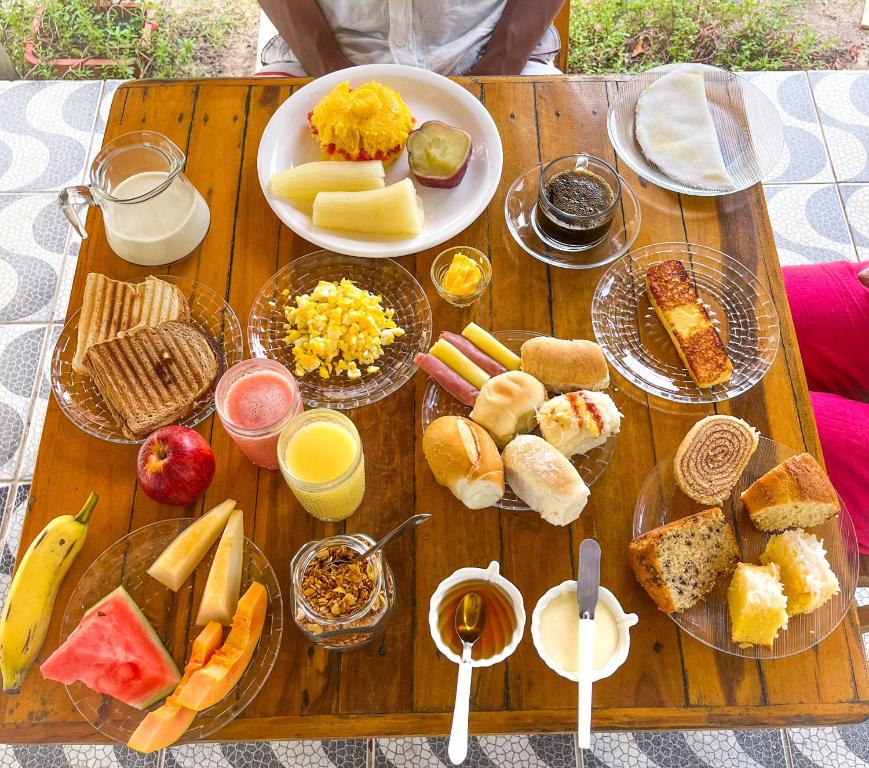 a wooden table topped with lots of different types of food at Pousada Carpe Diem - Apenas 6 suítes! in Porto De Galinhas