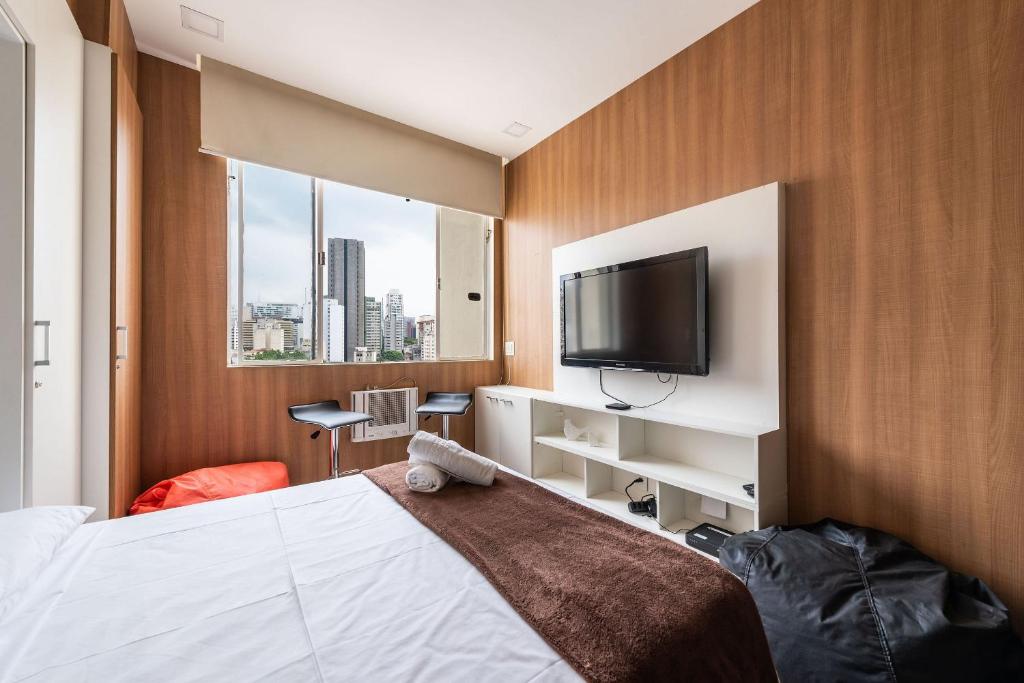 Habitación de hotel con cama y TV de pantalla plana. en AÃ - Studio Aconchegante em Higienópolis: Próximo ao Mackenzie e Metrô!, en São Paulo