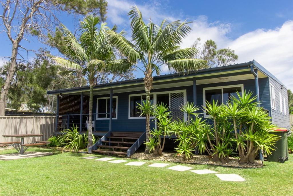 uma casa azul com palmeiras em frente em Silversands Beach House em Berrara