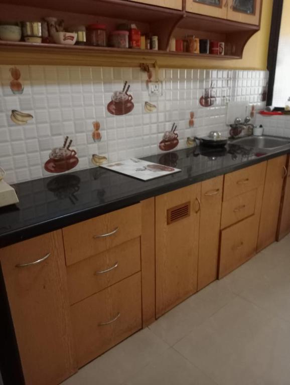 a kitchen with wooden cabinets and a black counter top at LUXURY 1 bedroom flat in Madgaon