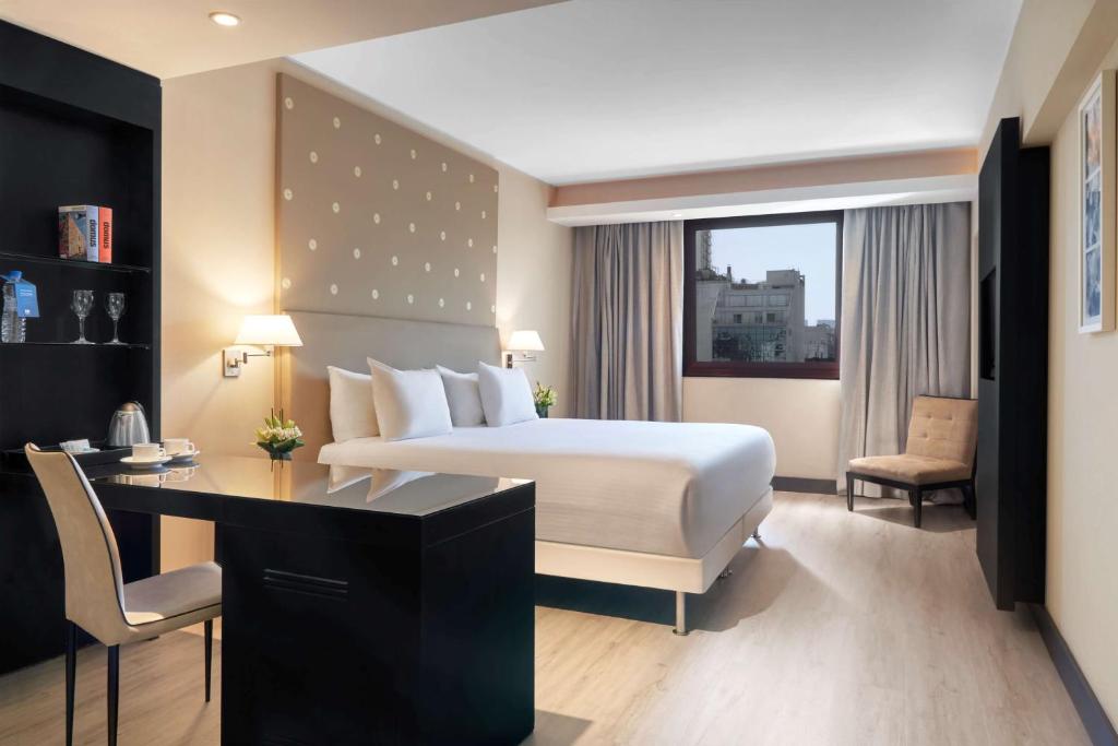 a hotel room with a bed and a desk and a desk at NH Buenos Aires 9 de Julio in Buenos Aires